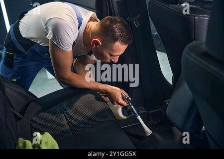 Worker thoroughly cleans the interior of a car using steam Stock Photo