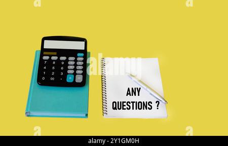 Text ANY QUESTIONS on a notepad on a yellow background with a calculator and pen Stock Photo