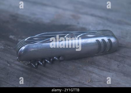 Multifunctional knife on the background of an old wooden table, close-up. Stock Photo