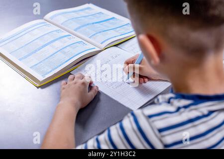 Boy is doing his homework in the kitchen. Stock Photo