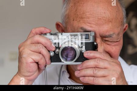 A senior man using a classic vintage camera to take photos. Stock Photo