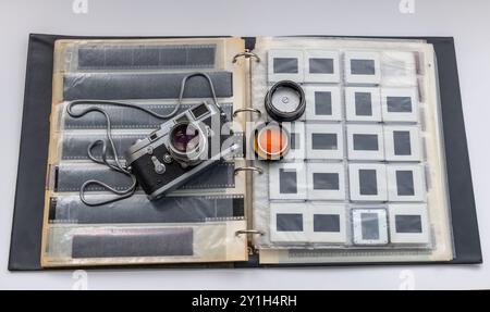 A classic vintage photo camera on a folder for holding slides and negative films, isolated in white. Stock Photo