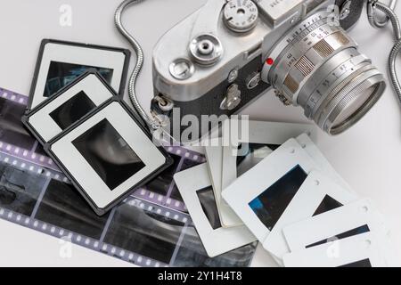 A classic vintage camera with photo filmstrip negatives and slides isolated in white. Stock Photo