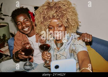 High angle shot of married couple holding wine glasses while taking selfie Stock Photo
