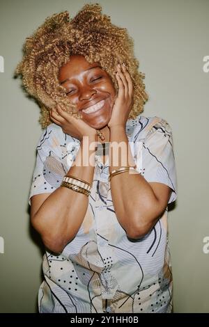 Vertical portrait of young blonde curly haired woman smiling widely Stock Photo