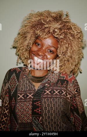 Portrait of blonde curly haired woman smiling widely while posing for photo Stock Photo