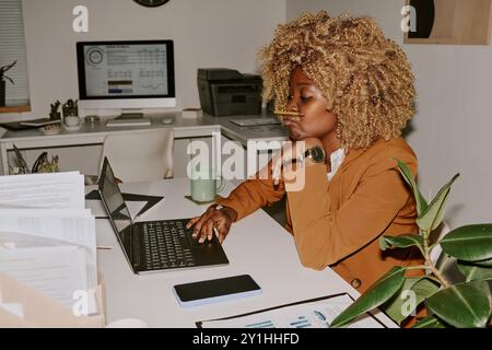 Female worker sitting at table and creating project in office Stock Photo
