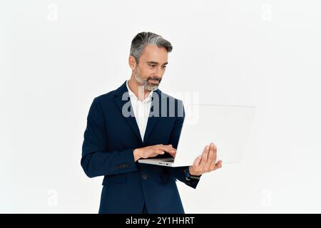 Busy mature business man using laptop standing isolated on white background. Stock Photo
