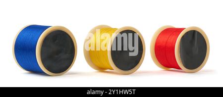 primary colors spool of cotton embroidery sewing thread isolated white background, blue, yellow and red used in detail stitching or decorative fabric Stock Photo