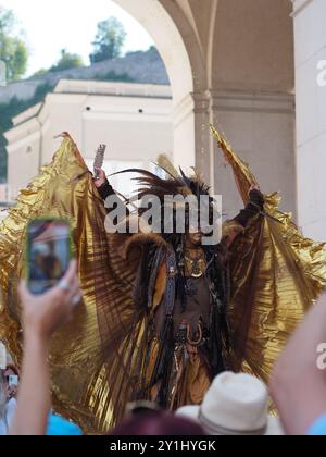 Salzburg, Austria - 31 Aug, 2024: An individual dressed in elaborate festive costumes with large feathered headpieces and ornate accessories posing in Stock Photo