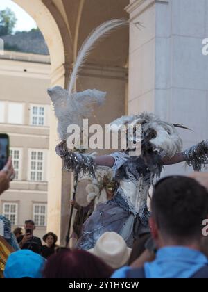 Salzburg, Austria - 31 Aug, 2024: An individual dressed in elaborate festive costumes with large feathered headpieces and ornate accessories posing in Stock Photo