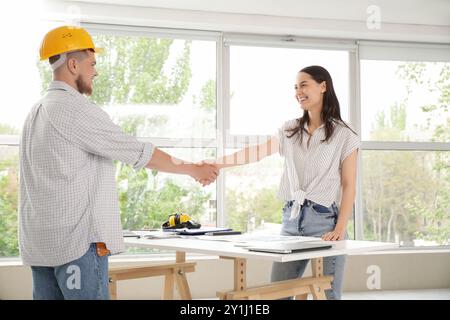 Male contractor with client shaking hands in room Stock Photo