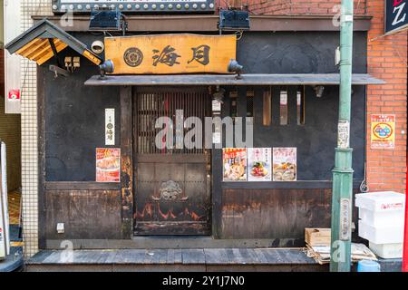 Typical traditional Japanese restaurant in the Kabukicho entertainment district of Shinjuku. Dark frontage of wooden and iron with slats for windows. Stock Photo