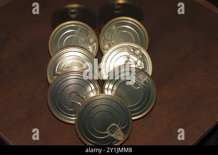 Close-up of a group of closed tin cans with a key to open them. Stock Photo