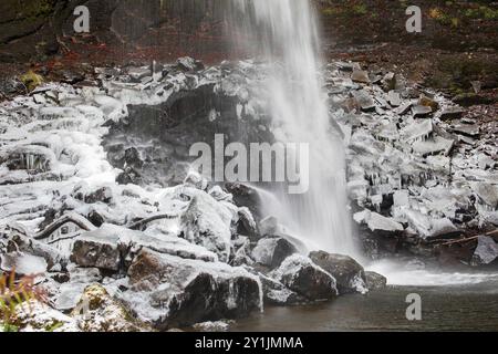 Rocks at the base of Hardraw Force, England's highest waterfall, are coated with ice on a snowy winter day in December Stock Photo
