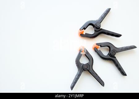 Three black plastic spring clamps over white background with copy space available. Stock Photo