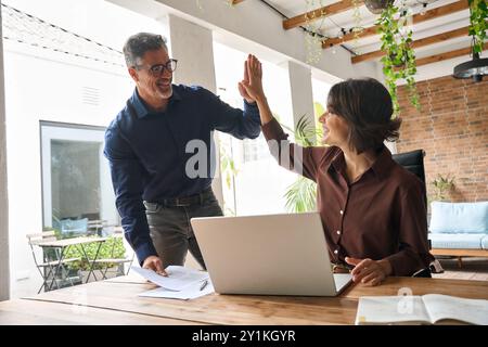 Two happy professional business team people man and woman giving high five. Stock Photo
