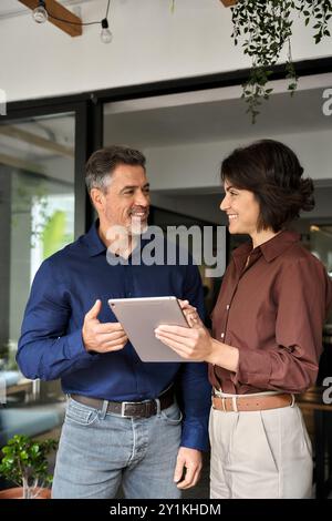 Happy busy company managers using tablet working together standing in office. Stock Photo