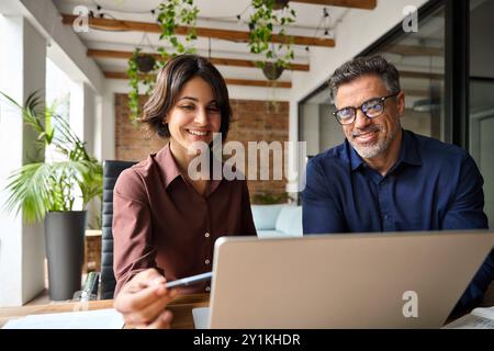 Two happy busy male and female business people working at desk using laptop. Stock Photo