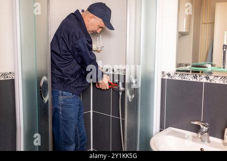 The mature plumber changing the shower faucet  using work tool pliers, close-up photo. Plumbing, repairing, assemble concept. Stock Photo