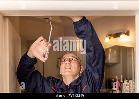 An electrician checking the phase of the electric wire, using an electric tester. Stock Photo