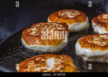 Cottage cheese pancakes are fried in a pan before being pulled out Stock Photo