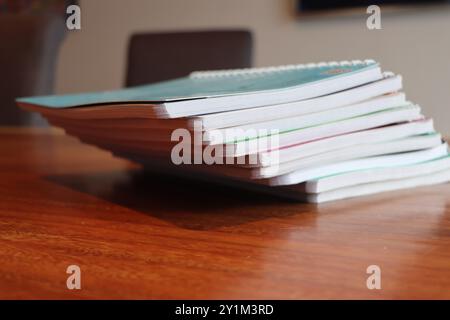 Stack of Spiral Notebooks and Reports on Wooden Desk Stock Photo