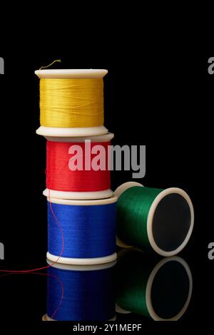 spools of cotton embroidery sewing thread isolated black background with reflections, used in detail stitching or decorative fabric and textile indust Stock Photo