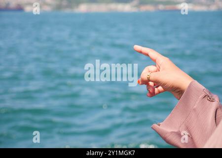 A closeup image of a female hand pointing over water in a natural outdoor setting Stock Photo