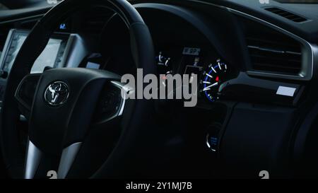 Luxurious sleek car dashboard with dark, powerful aesthetic interior. In image Toyota Innova Crysta with elegant badging in the steering. Stock Photo