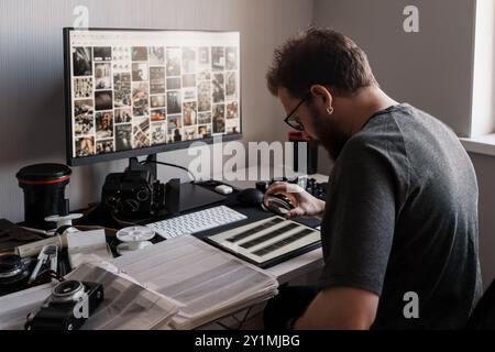 Photographer reviewing film negatives at a computer workstation Stock Photo