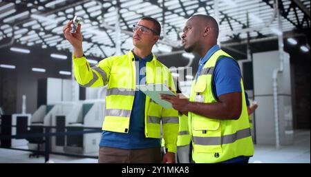 Factory Engineers Examining CNC machine parts. Engineering Facility Paperwork Stock Photo