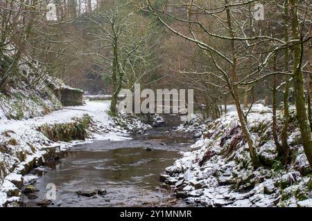 An arched wooden footbridge over Hardraw Beck, near Hardraw Force on a snowy winter day in December Stock Photo