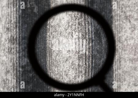 Old and very dangerous asbestos roof. View through magnifying glass. Asbestos dust in the environment. Health problems Stock Photo