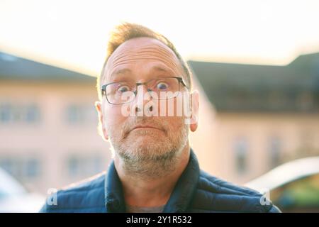 Outdoor close up portrait of middle age man with funny surprised facial expression Stock Photo