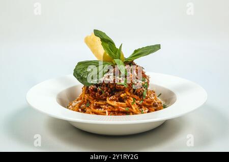 Delicious Italian pasta with spaghetti alla bolognese in tomato sauce in a white plate. Delicious dinner at the restaurant. Stock Photo