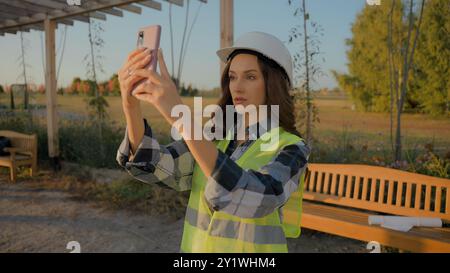 Professional Caucasian female woman businesswoman ecology engineer lady workwear using mobile phone cellphone device controller recording film video Stock Photo