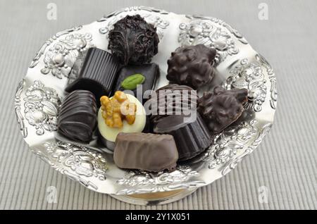 Different kinds of chocolate pralines on a silver plate, close up, isolated on white background Stock Photo