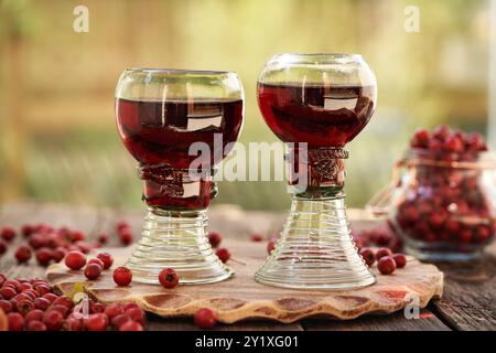Medicinal wine prepared from fresh hawthorn berries in two cups made of so called forest glass full of air bubbles Stock Photo