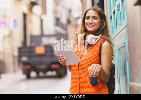 Student holding reusable water bottle while using digital tablet Stock Photo
