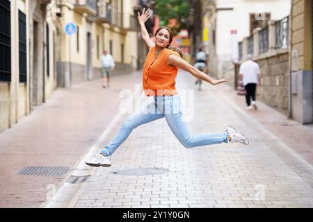 Woman jumping and opening arms in the city Stock Photo