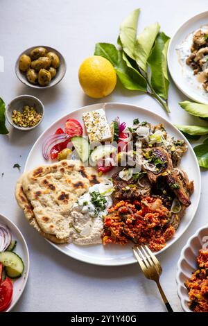 Greek food, lamb chops with couscous, feta salad, hummus and flat breads Stock Photo