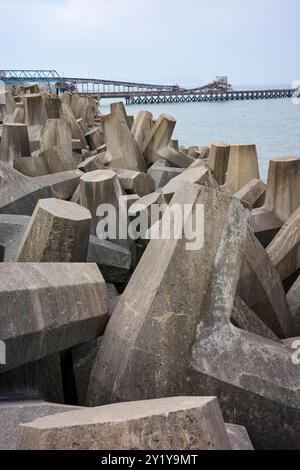 man made concrete sea wall defence defending the shore from the power of the sea. Stock Photo