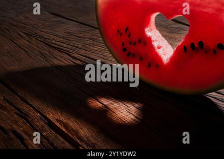 Ripe watermelon slice with heart shaped hole on blue background of the blue sky with little cloud on a hot summer day Stock Photo