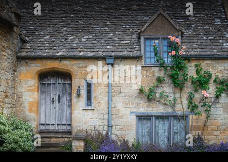 Charming English cottage with stone walls and blooming roses Stock Photo