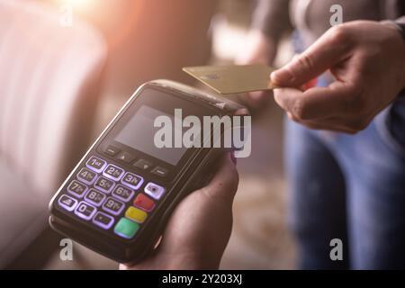 NFC credit card payment. Woman paying with contactless credit card with NFC technology. Wireless money transaction. Card machine in male hand on sunli Stock Photo