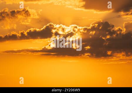 Natural yellow cloudy sunset background. Sunset sky. Dark clouds. Vibrant coloured glowing cloudscape Stock Photo