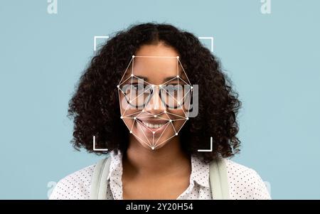 Woman smiling in front of a light blue background with facial recognition grid Stock Photo