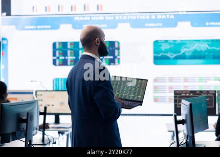 Administrative assistant examining important big data visualizations on a huge display, creating an analysis to review key performance indicators and business efficiency in office. Stock Photo