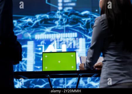 Green screen tablet used by computer scientists in startup doing advancements in AI field. Close up shot of employees working on mockup device in workspace featuring artificial intelligence systems Stock Photo